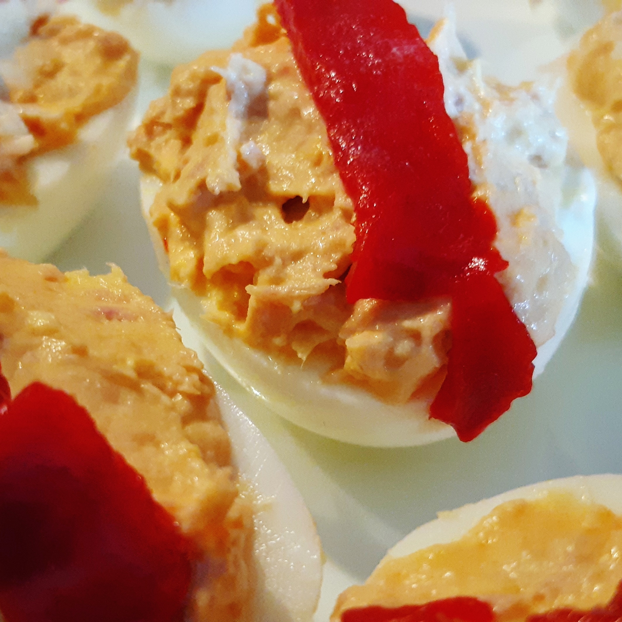 Receta fácil de huevos rellenos con atún y decorados con pimiento rojo, ideal para aperitivos y ocasiones especiales.